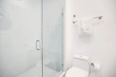a white bathroom with a shower and a toilet at Penthouse Sky Suite - 2BDR2BTH - Private Rooftop Terrace in Hallandale Beach
