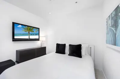 a bedroom with a white bed with a tv on the wall at Oceanfront 3B Private Residence at South Beach - 828 in Miami Beach