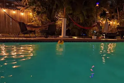 a swimming pool at night with a hammock and a swimming pool at Heated Pool Private Duplex House, BBQ, Parking, WiFi in Cutler Bay