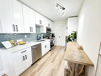 a kitchen with white cabinets and a wooden floor at AQUAMARIA HOME - perfect stay for groups in Fort Lauderdale