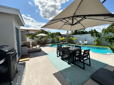 a patio with a table and an umbrella next to a pool at AQUAMARIA HOME - perfect stay for groups in Fort Lauderdale