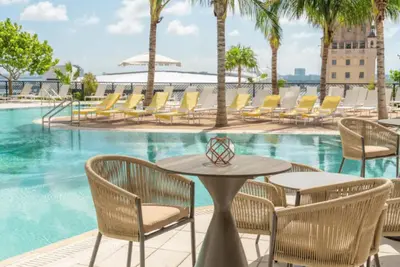a table and chairs next to a swimming pool at Lux 2BR Natiivo Condo With Pool, Spa and Gym Access in Miami