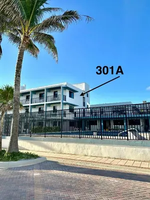 a building with a palm tree next to a fence at Beach Getaway in Hollywood