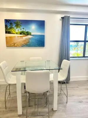 a dining room table with white chairs and a painting at Beach Getaway in Hollywood