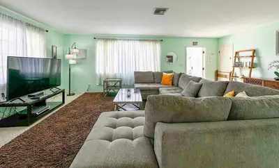 a living room with a couch and a flat screen tv at Sunrise Delight 2 min walk to Beach Essentials in Hollywood
