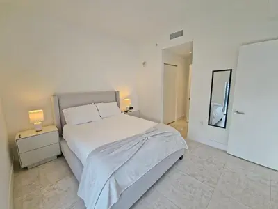 a white bedroom with a large bed and two lamps at Sleek New Brickell Condo With Free Parking - CS65 in Miami