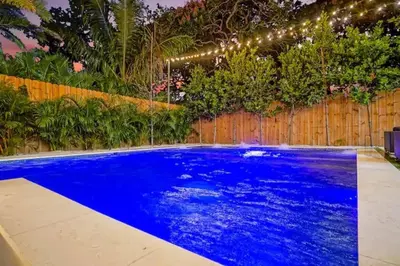 a blue swimming pool with lights on a fence at NEW Bali Resort Style Villa with Vast Pool & Jacuzzi and Outdoor Grilling in Miami