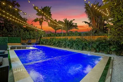 a large blue pool with lights and palm trees at NEW Bali Resort Style Villa with Vast Pool & Jacuzzi and Outdoor Grilling in Miami