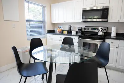 a kitchen with a glass table and black chairs at Cozy Central Stay Airport, KingBed, Fenced Parking - Little Havana Near Airport, Wynwood, Calle 8 Brickell, Coral Gables and more in Miami