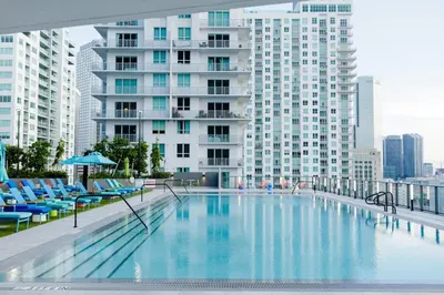 a large swimming pool with blue chairs and a tall building at The Bayfront VI in Miami