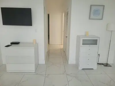 a white room with a television and a desk at Modern 1 BR Condo, Steps from Beach, Free Parking! in Sunny Isles Beach