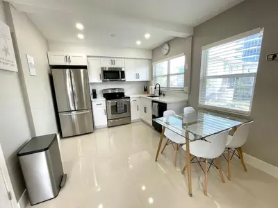 a kitchen with a glass table and a stainless steel refrigerator at Renovated Intercoastal 2Bdrm 1 bath condo Walk to Beach in Fort Lauderdale