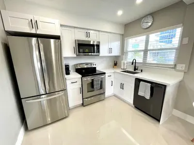 a kitchen with white cabinets and a stainless steel refrigerator at Renovated Intercoastal 2Bdrm 1 bath condo Walk to Beach in Fort Lauderdale