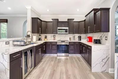 a kitchen with dark brown cabinets and wooden floors at Luxury Tropical Living , 4BR w Backyard Pool Oasis in Hialeah