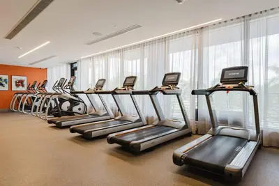 a row of treadmills in a gym with windows at Wonderful 2 bedroom Apartment in Downtown Doral in Miami