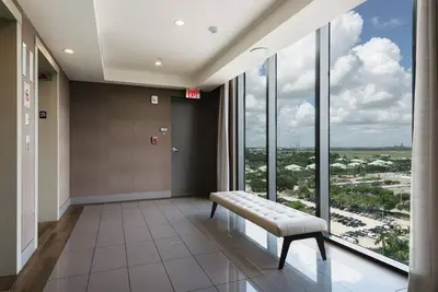 a waiting room with a bench and large windows at Wonderful 2 bedroom Apartment in Downtown Doral in Miami