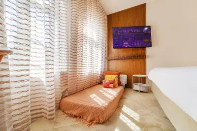 a bedroom with a couch and a tv on a wall at Casa Victoria Orchid Hotel in Miami Beach