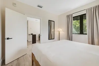 a white bedroom with a large bed and a window at Roami at The Palace in Miami