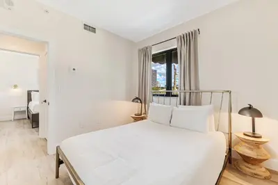 a white bedroom with a bed and a window at Roami at The Palace in Miami