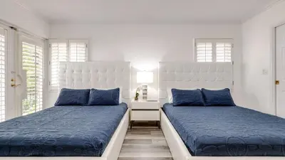 two beds in a white room with blue pillows at 5mins to Beach • Pool Hot Tub • Billiards Coral Ridge Getaway by AvantStay in Fort Lauderdale