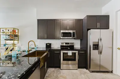 a kitchen with black cabinets and stainless steel appliances at Prime 2BR Near FLL Airport, Dania Beach & Pointe in Fort Lauderdale