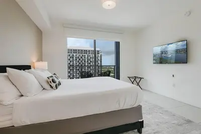 a white bedroom with a large bed and a large window at Wonderful Studio Apartment in Downtown Doral in Miami