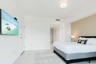 a bedroom with a large bed and a tv on the wall at Wonderful Studio Apartment in Downtown Doral in Miami