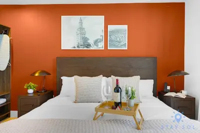 a bedroom with a white bed with an orange wall at Chic Downtown - City Views Gym & Pool in Miami