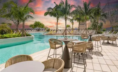 a resort pool with tables and chairs and palm trees at Oasis Apartment 1 Bedroom with Pool & Gym in Miami