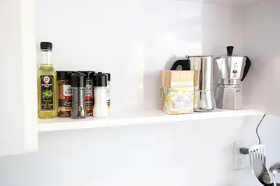 a shelf with bottles of alcohol and other items on it at 3 Minute Walk to Miami Beach Family and Pet Friendly Apartment in Miami Beach