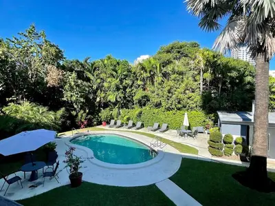 a swimming pool with chairs and a palm tree at 2Bdrm 1Bath Newly Renovated Condo - Walk to the Beach! in Fort Lauderdale