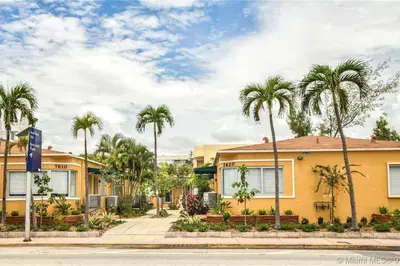 a yellow house with palm trees in front of a street at Family Pet Friendly Apartment 3 Minute Walk to Miami Beach in Miami Beach