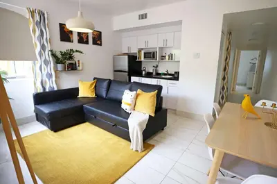 a living room with a black couch and yellow pillows at Family Friendly Condo Steps to Miami Beach with Free Parking in Miami Beach