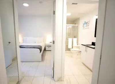 a white bedroom with a bed and a bathroom at 3 Bedroom 3 Bathroom Miami Beach Apartment in Miami Beach