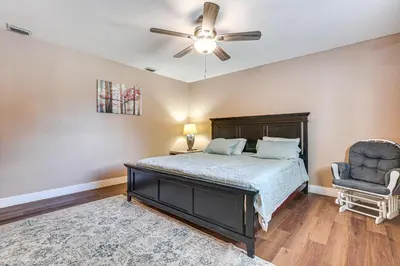 a bedroom with a bed and a ceiling fan and a chair at 11 Mi to South Beach Home with Screened Porch! in Miami