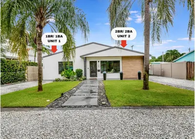 a house with two palm trees in front of it at Lovely 2BR 2BA Modern Flat with Vibrant Backyard in Fort Lauderdale