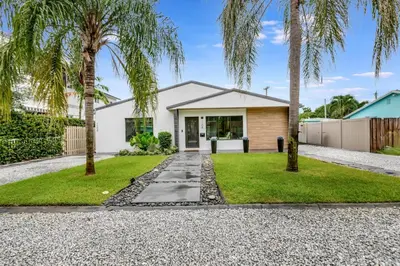 a house with palm trees in front of it at Lovely 2BR 2BA Modern Flat with Vibrant Backyard in Fort Lauderdale
