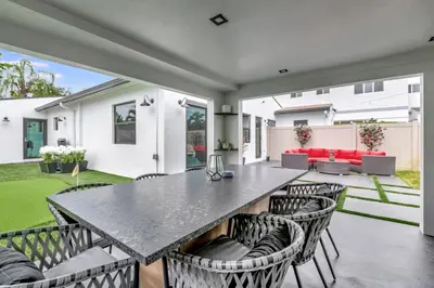 a patio with a large table and chairs at Lovely 2BR 2BA Modern Flat with Vibrant Backyard in Fort Lauderdale