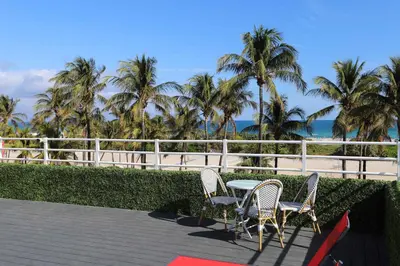 a table and chairs on a patio with palm trees at Ocean Drive Oasis in Art Deco District of South Beach in Miami Beach