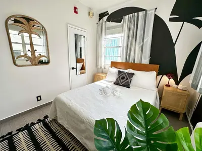 a bedroom with a bed and a mirror and plants at Beachfront Ocean Drive South Beach Miami in Miami Beach