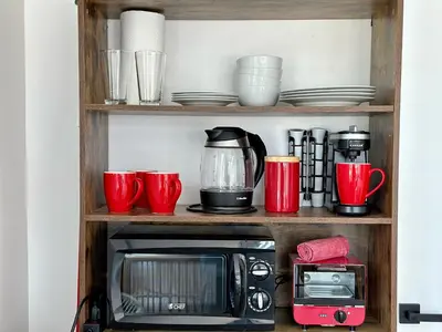 a shelf with a microwave and cups and dishes at Ocean Drive Oasis Beach Views South Beach Miami in Miami Beach