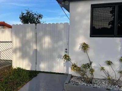 a white fence next to a house with flowers at Spacious Private Room Close to Miami Attractions in Miami