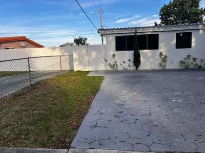 a white house with a fence and a driveway at Spacious Private Room Close to Miami Attractions in Miami