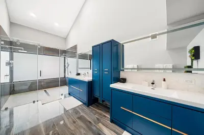 a bathroom with blue cabinets and two sinks and a shower at Best Bayfront View Villa with Heated Pool in North Bay Village