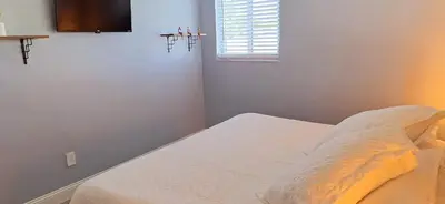 a bedroom with a bed and a television on the wall at Holliday 3-bedroom Private duplex House Parking WiFi BBQ Karaoke Available in Cutler Bay