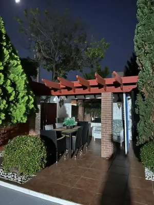 a pergola with chairs and a table in a garden at R&R Hostal in Miami