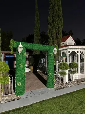 a hedge arch in front of a white house at R&R Hostal in Miami