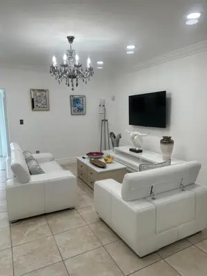 a living room with white furniture and a flat screen tv at R&R Hostal in Miami