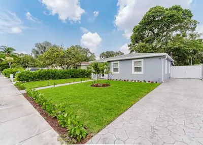 a white house with a green yard at BOHO Elegance in the FLL city! in Fort Lauderdale