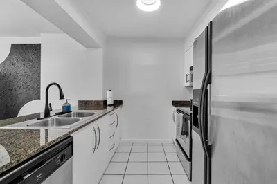 a white kitchen with a sink and a refrigerator at Stylish 1BR Brickell Condo with Balcony and Pool Access in Miami